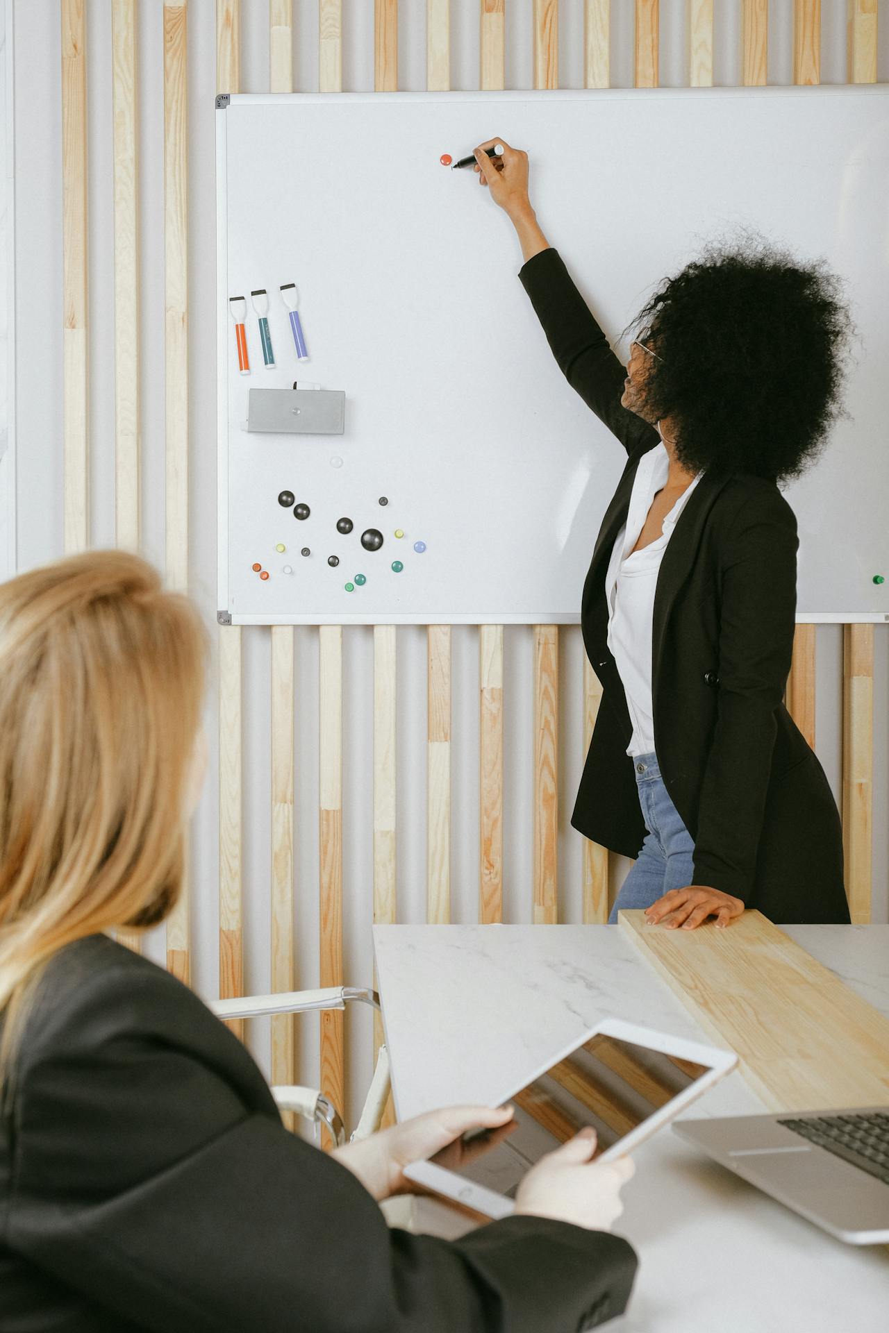 Female teacher writing on the board with colored markers