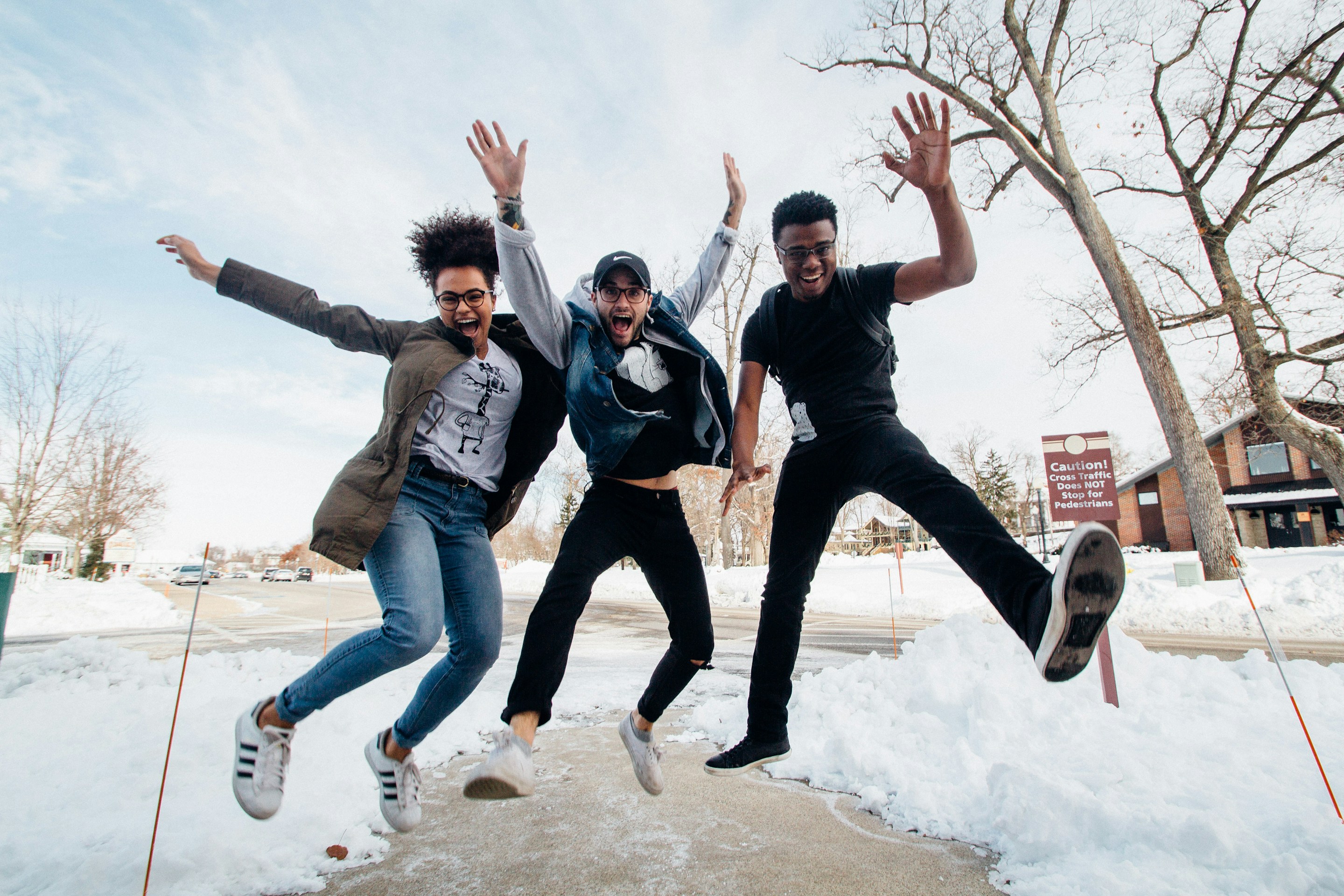 Three students jumping on a floor covered with snow