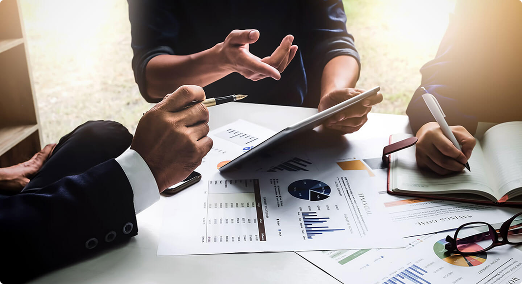 Three individuals in a meeting discussing charts